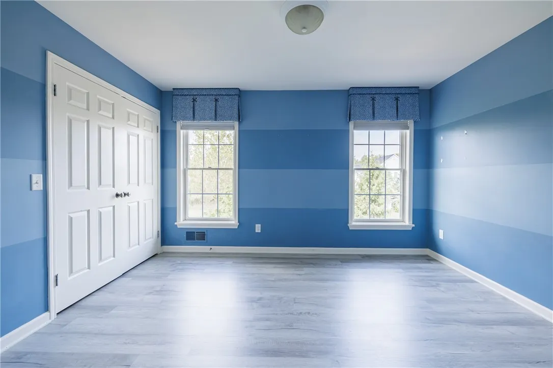 Bedroom 2 with luxury vinyl flooring, custom window coverings, and large closet.