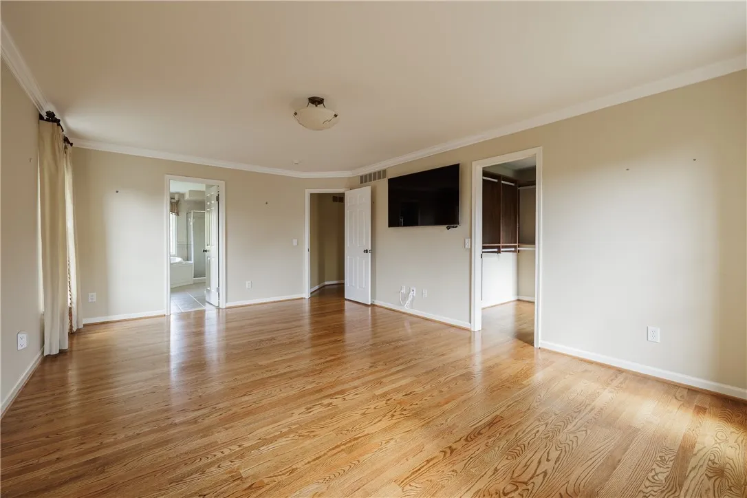 Large, bright primary bedroom with gleaming hardwoods and two walk-in closets!