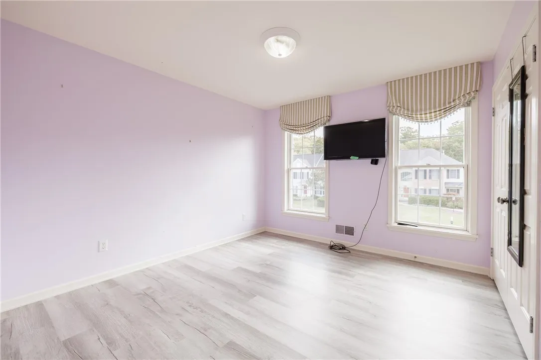 Bedroom 3 with luxury vinyl flooring, mounted TV and custom window treatments.