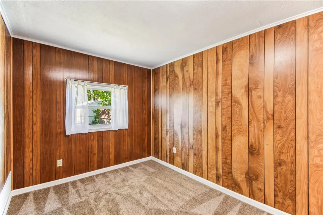 THE 1ST FLOOR BEDROOM HAS PANELED WALLS, WINDOW AND WALL-TO-WALL CARPETING.