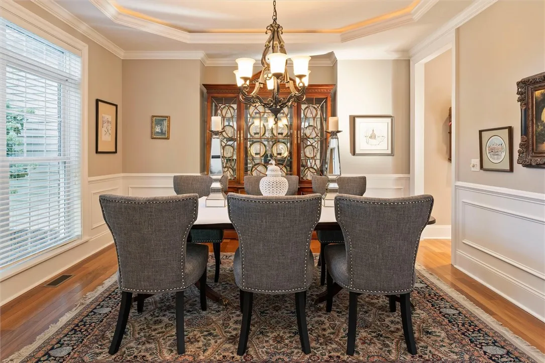 Formal dining room designed for memorable gatherings — featuring elegant wainscoting, tray ceiling with accent lighting, and abundant natural light that enhances every detail.