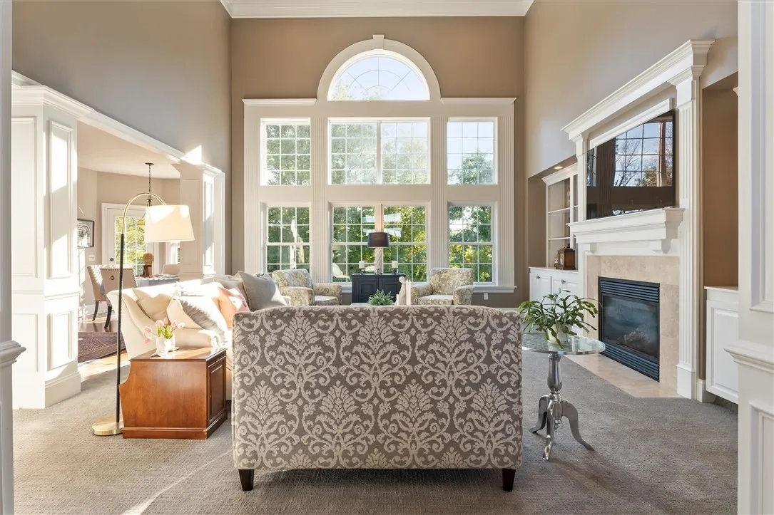 The great room impresses with soaring ceilings, a dramatic wall of windows, and a catwalk overlook that enhances the open feel. A gas fireplace anchors the space, creating a cozy yet grand gathering area filled with natural light and beautiful views.