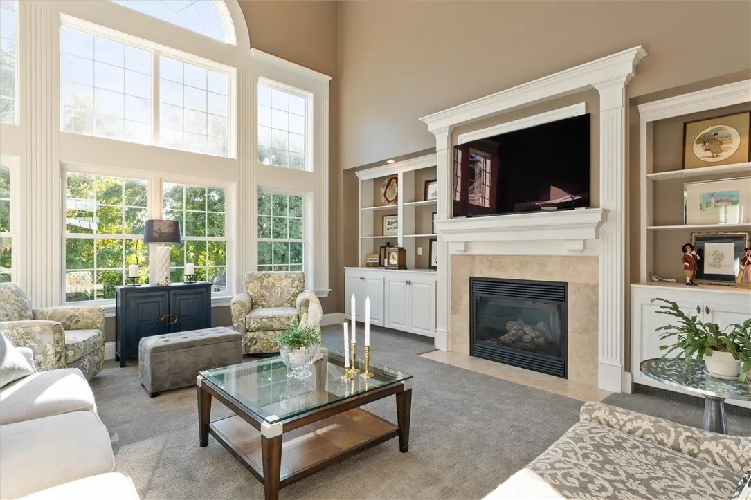 The great room impresses with soaring ceilings, a dramatic wall of windows, and a catwalk overlook that enhances the open feel. A gas fireplace anchors the space, creating a cozy yet grand gathering area filled with natural light and beautiful views.