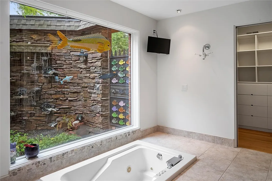 Primary jetted tub overlooking waterfall wall and outdoor shower
