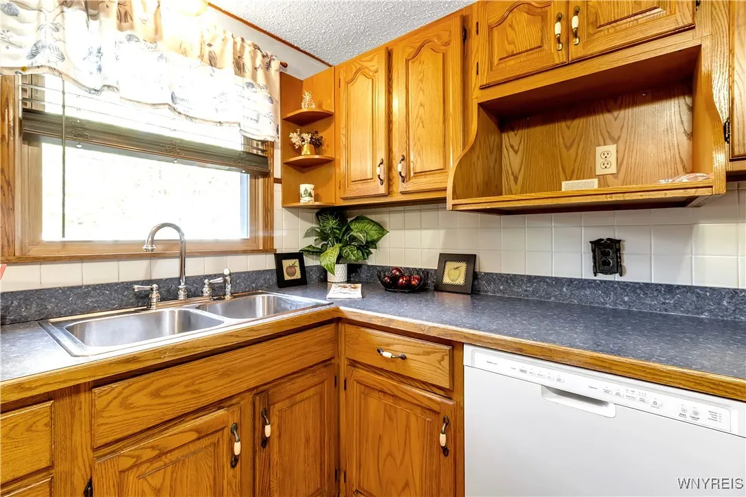 Kitchen has double stainless style sinks, microwave shelf, lbuilt-in dishwasher lots of oak style cabinetry
