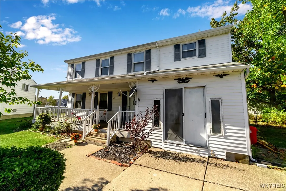 Close up front yard views with inviting covered porch + concrete walkway + driveway
