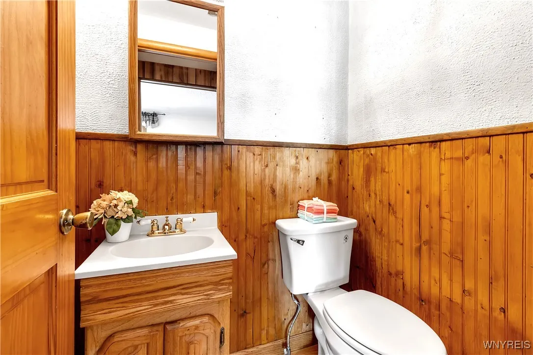 Half bath with wood style vanity, wainscotd walls + mirrored medicine