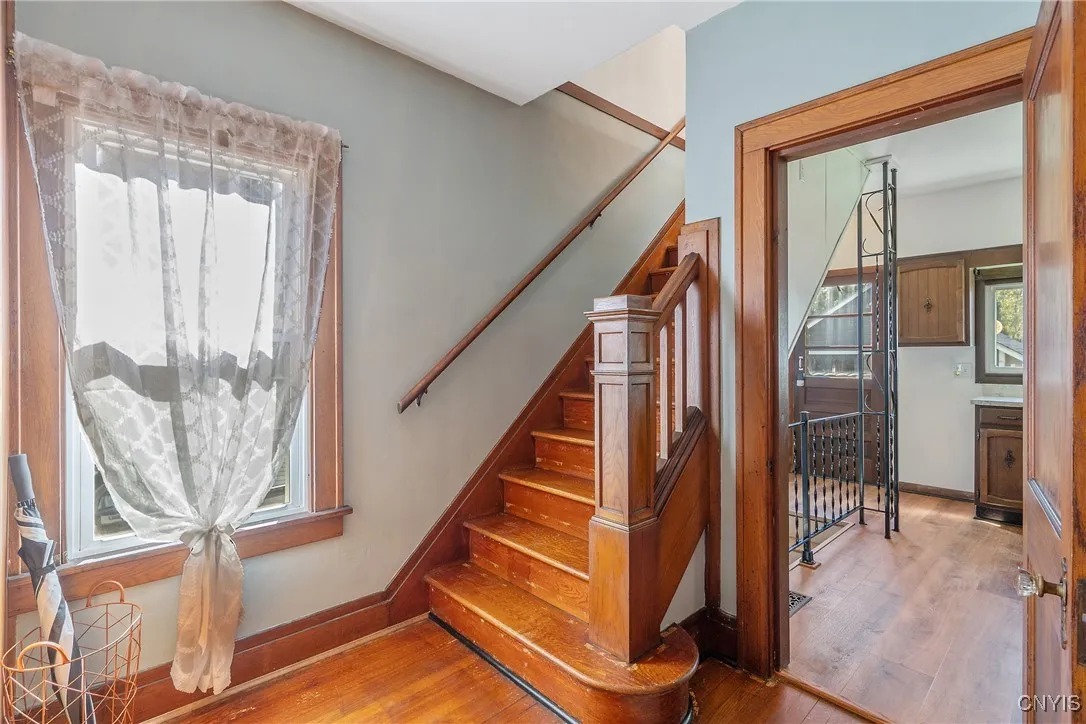 From the front door, one can head upstairs, straight into the kitchen, or right to the living room. Note the huge window. gleaming hardwood floors and gorgeous wood banister and trim.