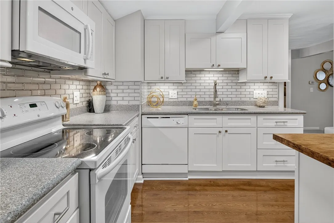 NICELY APPOINTED KITCHEN W/ CORIAN & BUTCHER BLOCK COUNTERTOPS * HARDWOOD FLOORING * GLASS SUBWAY TILED BACKSPLASH * SOFT CLOSE CABINETS W/ UNDER CABINET REMOTE CONTROLLED LIGHTING