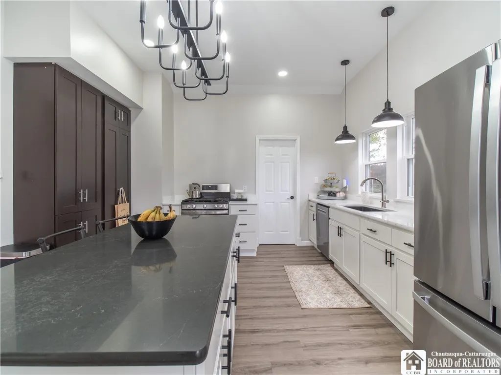 Custom cabinetry with quartz countertops and all stainless appliances. The stove and dishwasher will convey at closing. The walk-in pantry is located through this door.