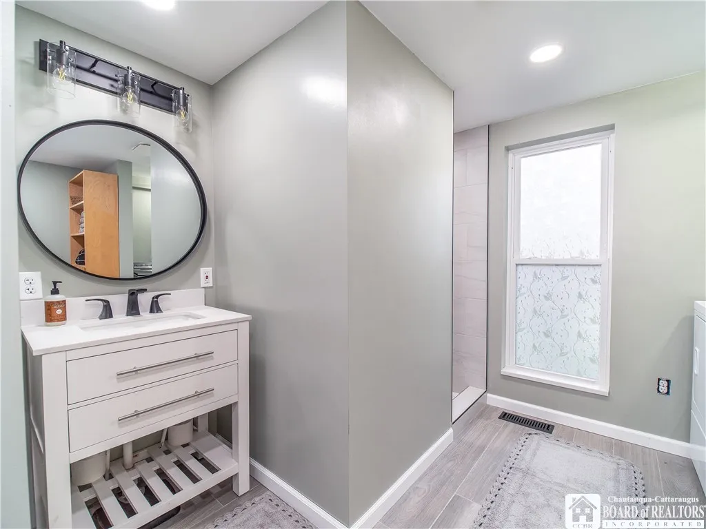 Bright and cheerful bathroom features a custom shower surround and vanity.