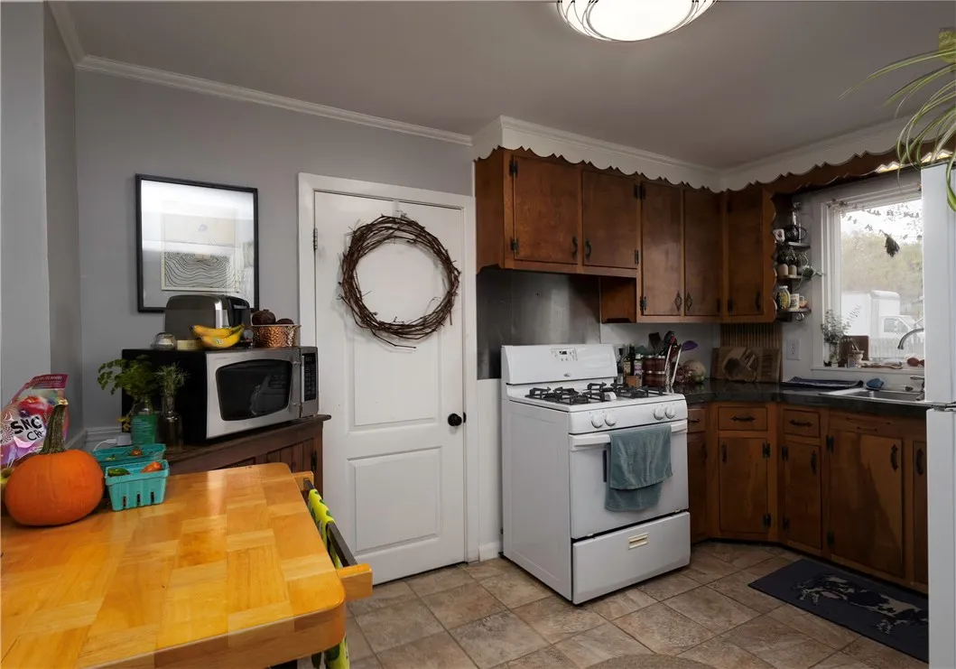 Bright and functional kitchen featuring classic wood cabinetry, tile flooring, and entry to backyard through the laundry and furnace room