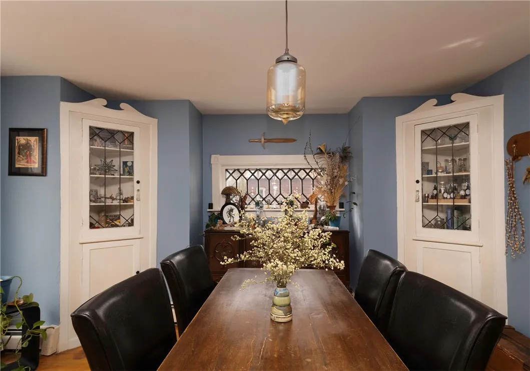 Charming dining area featuring built-in glass-front cabinets, wood floors, and leaded glass windows.