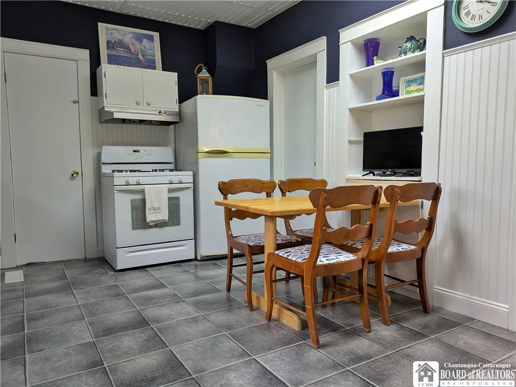 Eat in kitchen with shelving for storage  and a tv, bead board on the walls