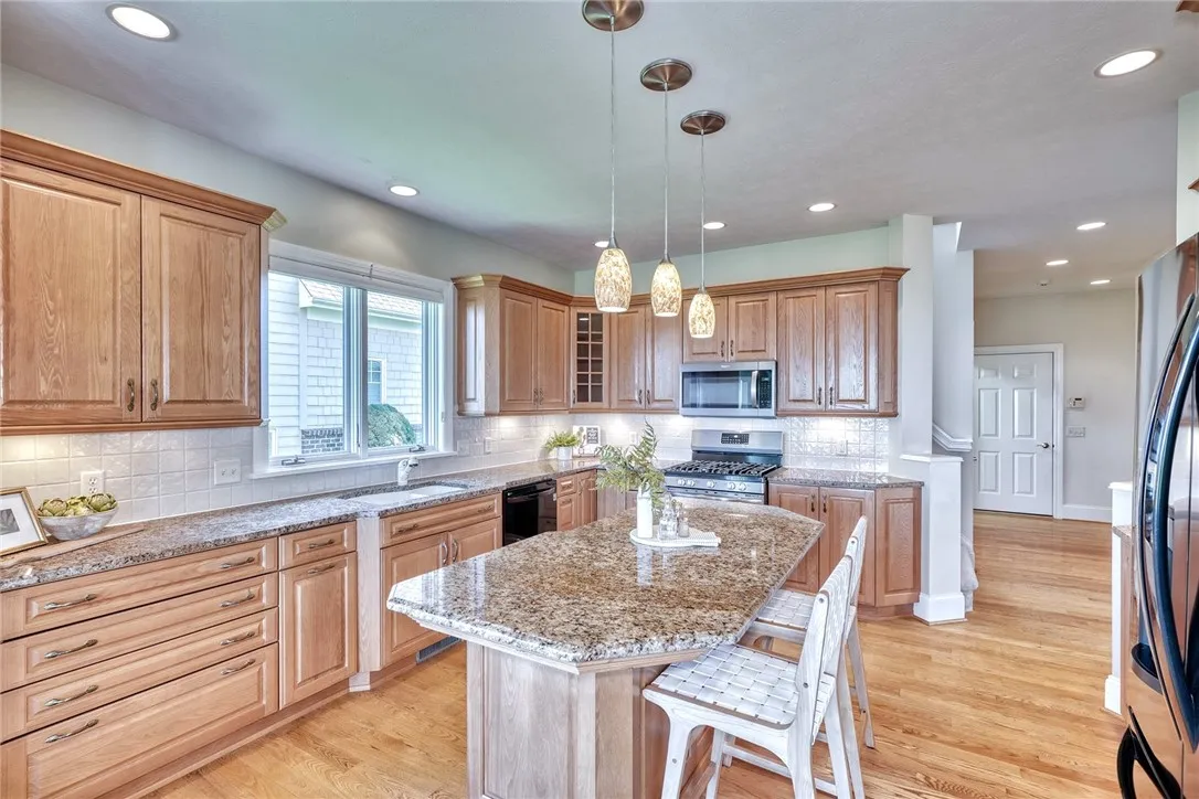 The kitchen blends beauty and practicality with quality cabinetry, granite counters, tile backsplash, and a center island — plus a spacious walk-in pantry that keeps it all effortlessly organized.