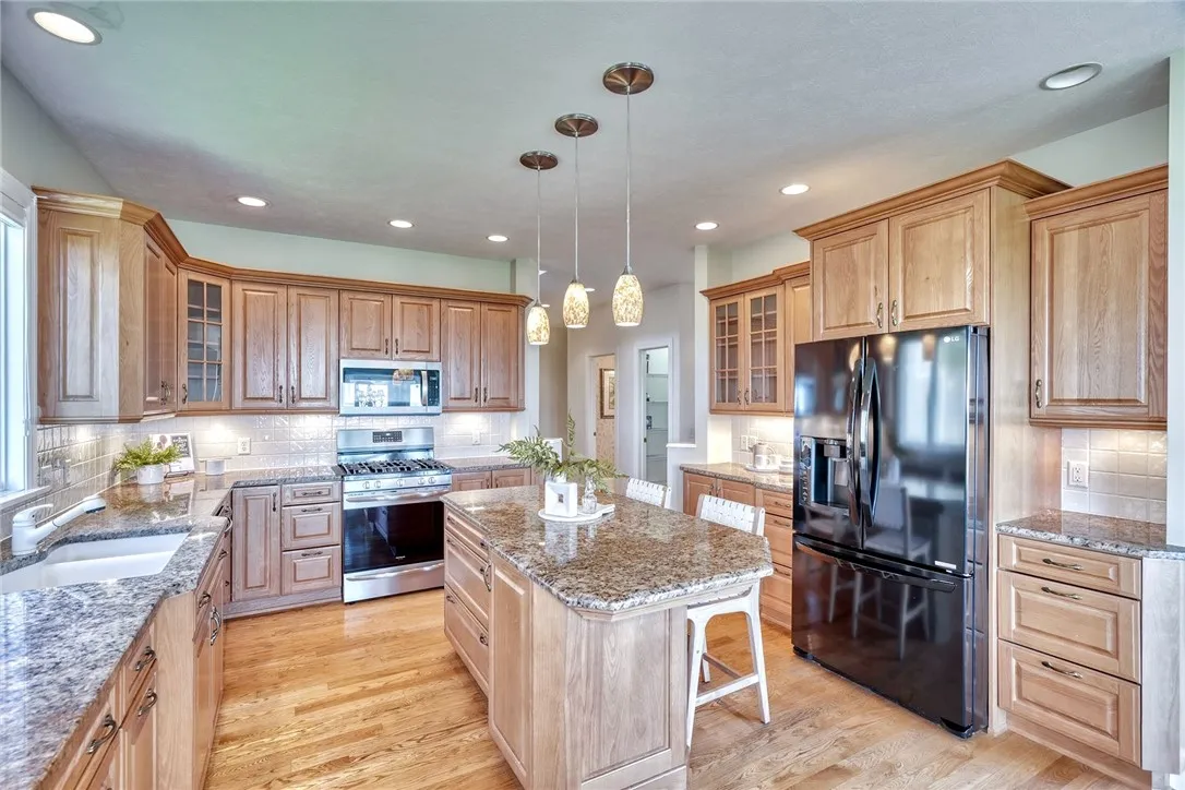 The kitchen blends beauty and practicality with quality cabinetry, granite counters, tile backsplash, and a center island — plus a spacious walk-in pantry that keeps it all effortlessly organized.