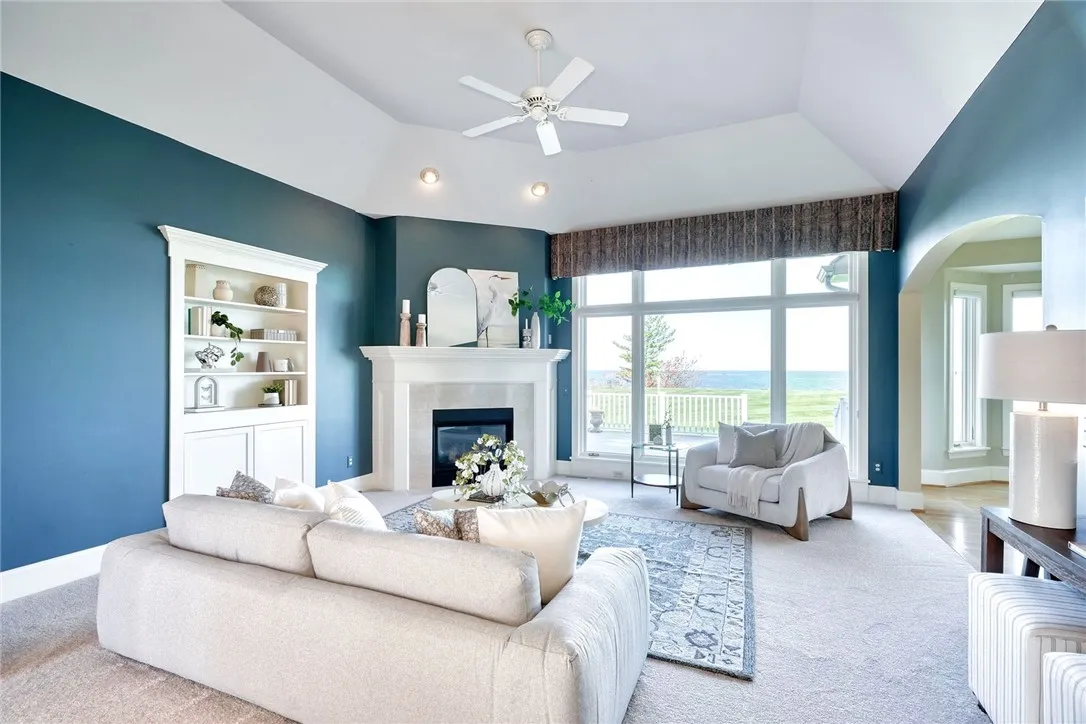 Great room with volume ceilings, anchored by a gas fireplace and built-ins—framed by that wall of glass!