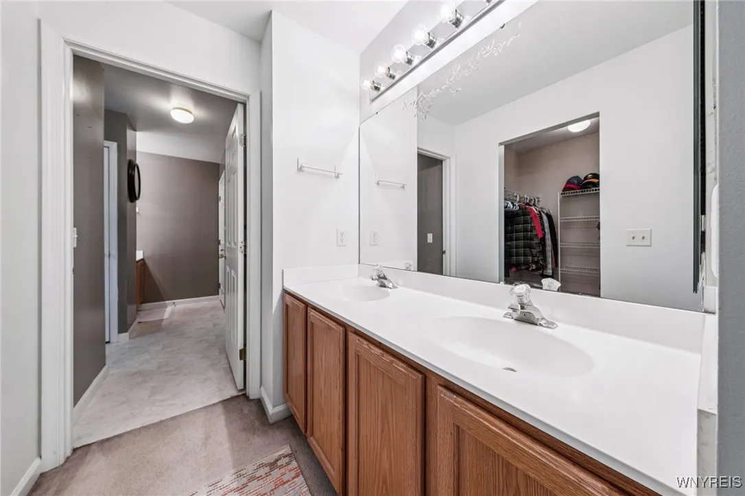multiple sinks and large mirror near closet for easy readiness in the morning adjoining primary bedroom