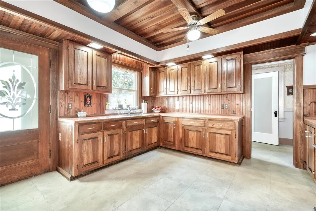 The kitchen brings warmth and function — custom wood ceiling, rich cabinetry, long runs of counters, and space for an island or big eat-in table