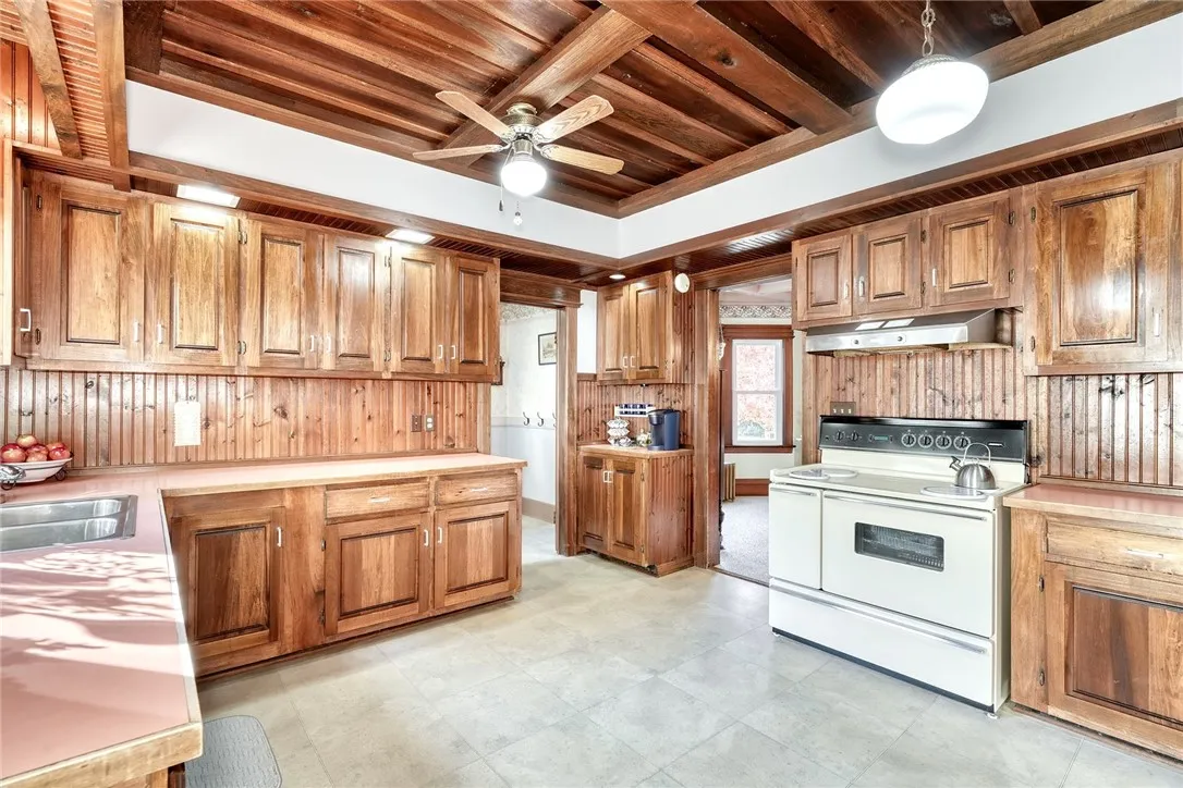 The kitchen brings warmth and function — custom wood ceiling, rich cabinetry, long runs of counters, and space for an island or big eat-in table