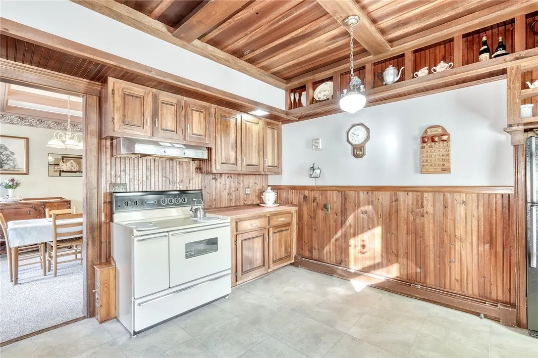 The kitchen brings warmth and function — custom wood ceiling, rich cabinetry, long runs of counters, and space for an island or big eat-in table