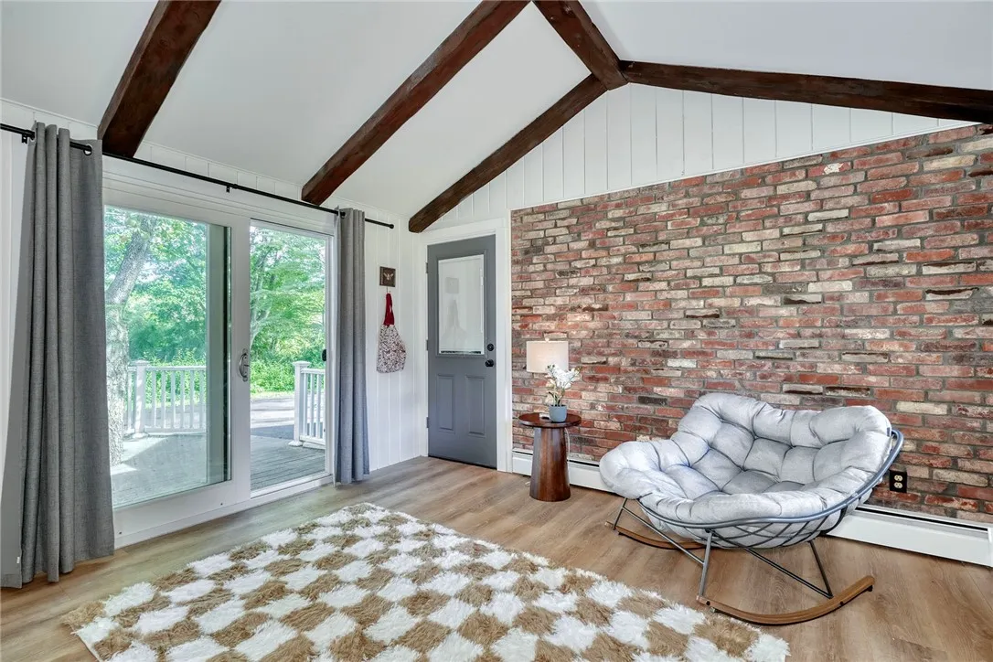 Vaulted bonus room with beams, brick wall, and slider to deck - Flexible uses!! Perfect for office, mudroom, or sitting room.