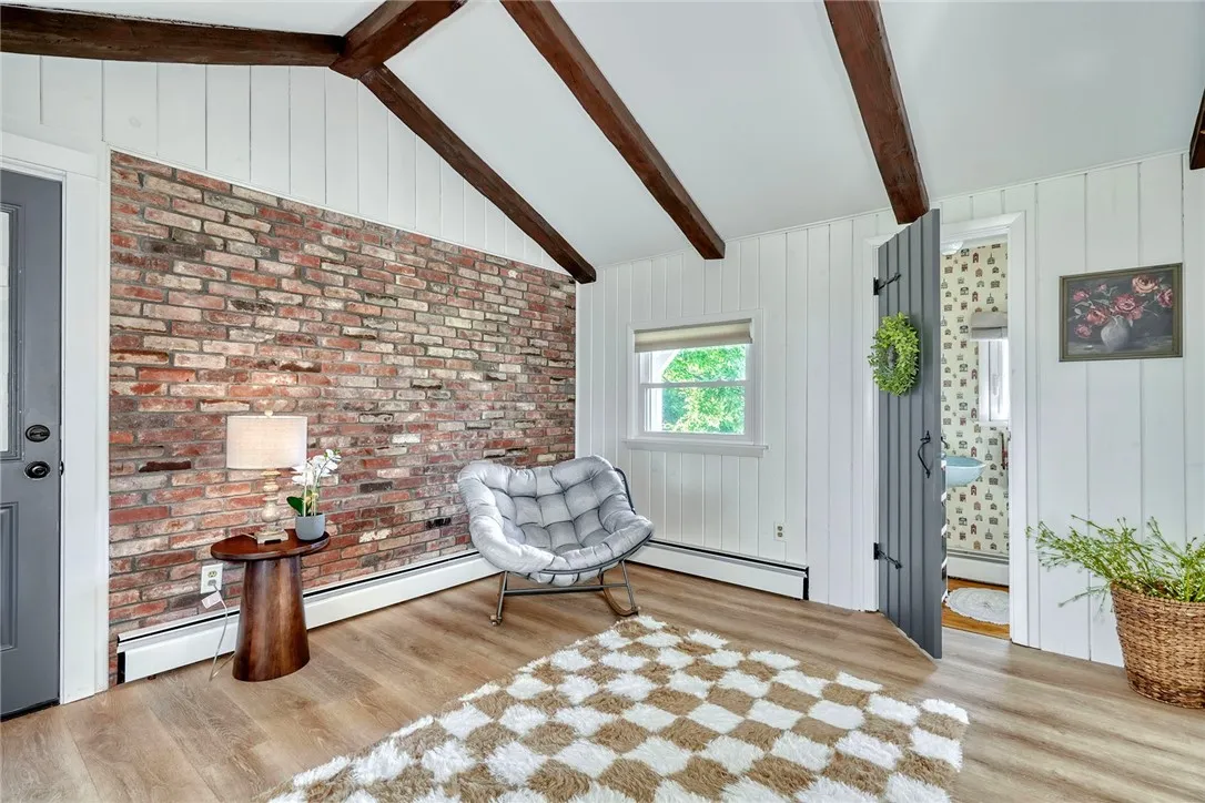 Vaulted bonus room with beams, brick wall, and slider to deck - Flexible uses!! Perfect for office, mudroom, or sitting room.
