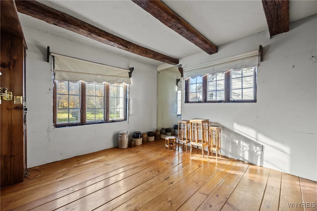 first floor bedroom with plank wood floors and beamed ceiling
