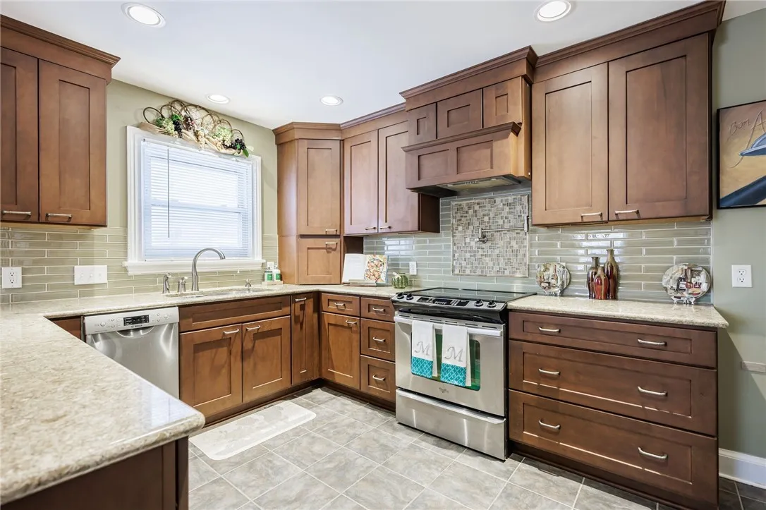 Beautifully Updated Kitchen features updated cabinetry, quartz counters, glass tile backsplash, ceramic tile floor and stainless steel appliances.
