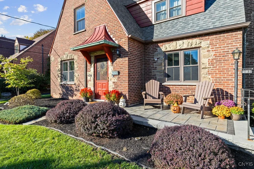 Newly stone front porch and walkway with freshly landscaped beds.The brick front and metal roof show its era.