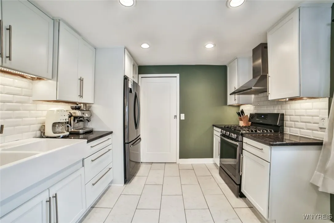 The beautifully updated kitchen is timeless, offering pretty white cabinetry and easy to maintain ceramic flooring and backsplash. The door ahead in this view leads to the laundry/utility room and side entrance to the home.