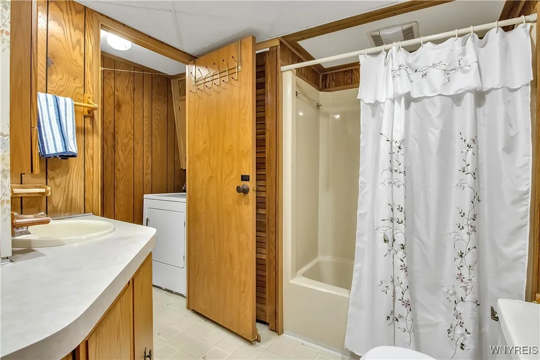 Full Bath with tub surround + door to laundry area with washer + dryer