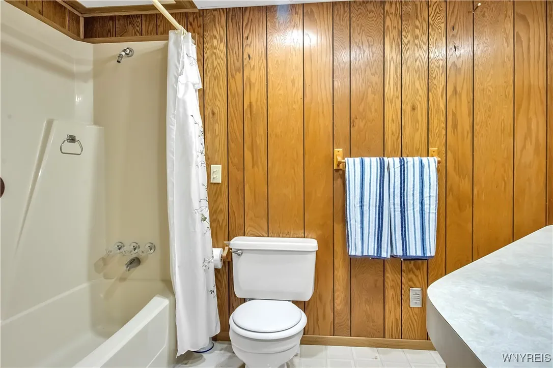 Full Bath with tub surround, towel racks + commode