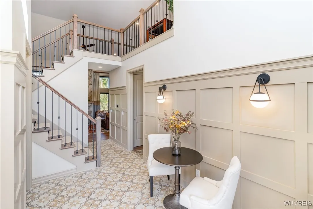 As you arrive, a spacious full front porch sets a warm and inviting first impression. Inside, a dramatic two-story foyer welcomes you and opens seamlessly into a bright, open-concept living space designed for both everyday comfort and effortless entertaining. Elegant custom wainscoting and thoughtfully selected designer lighting add architectural interest and a refined sense of sophistication, creating a stunning introduction to the home.