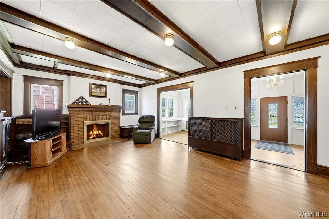 Check out the expansive living area featuring beamed ceilings, hardwood flooring and a wood-burning fireplace.