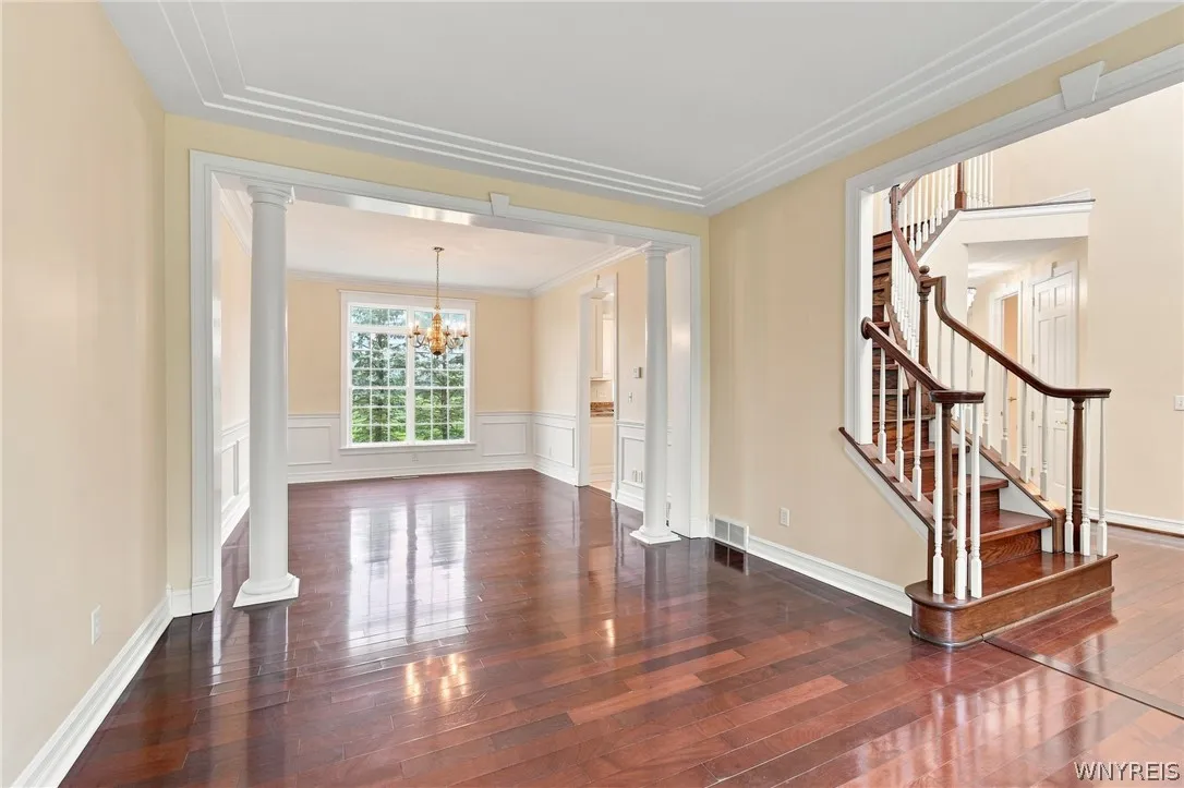 Perfect for entertaining, the elegant living & dining rooms flow seamlessly together in a beautiful,open-concept design.Just off the front foyer, the formal living room welcomes guests w/ stunning Rosewood floors,rich crown molding,& expansive windows framing serene outdoor views.Transitioning effortlessly into the formal dining rm, featuring timeless architectural details including classic wainscoting & an ornate brass chandelier.
