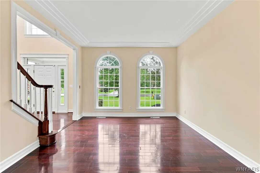 Perfect for entertaining, the elegant living & dining rooms flow seamlessly together in a beautiful,open-concept design.Just off the front foyer, the formal living room welcomes guests w/ stunning Rosewood floors,rich crown molding,& expansive windows framing serene outdoor views.Transitioning effortlessly into the formal dining rm, featuring timeless architectural details including classic wainscoting & an ornate brass chandelier.