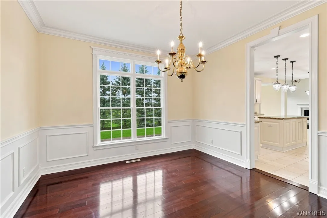 Perfect for entertaining, the elegant living & dining rooms flow seamlessly together in a beautiful,open-concept design.Just off the front foyer, the formal living room welcomes guests w/ stunning Rosewood floors,rich crown molding,& expansive windows framing serene outdoor views.Transitioning effortlessly into the formal dining rm, featuring timeless architectural details including classic wainscoting & an ornate brass chandelier.