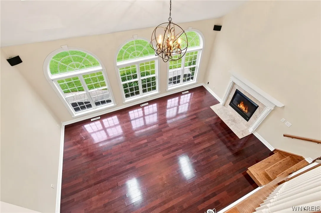The family room flows seamlessly into the kitchen, anchored by magnificent Rosewood floors and a cozy gas fireplace. Overhead, an elegant orbital crystal chandelier highlights the dramatic cathedral ceiling, while spectacular triple picture windows with palladium accents fill the space with natural light. A second staircase offers convenient access to the upper level.
