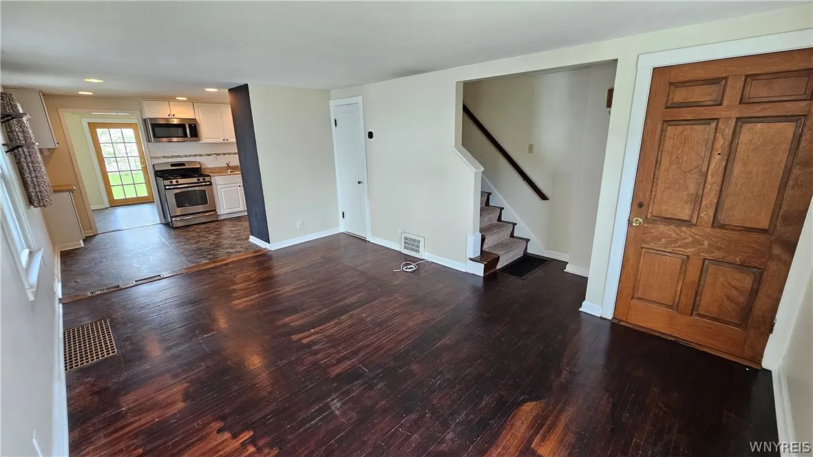 Living room looking to bonus room, eat-in kitchen, staircase to second floor and front door entry