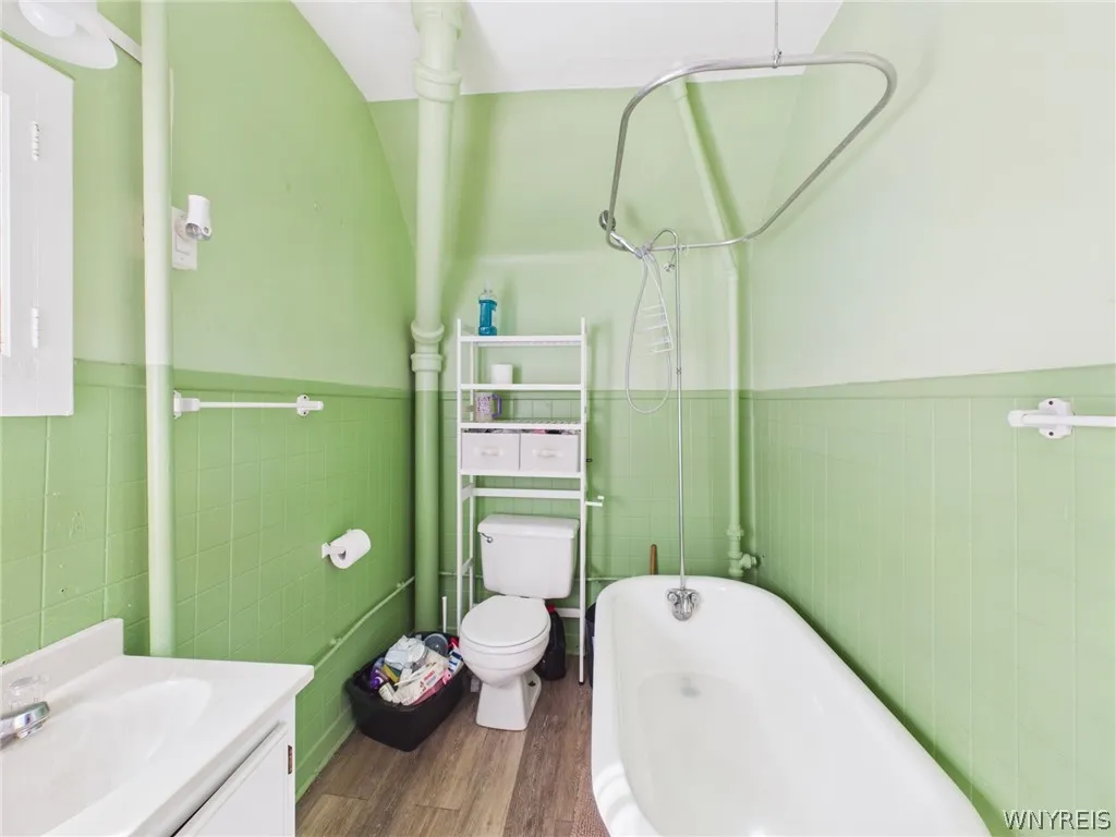 Full Bathroom: A full bath with a clawfoot tub, a handheld shower, a tiled wainscot, a vanity and a window.