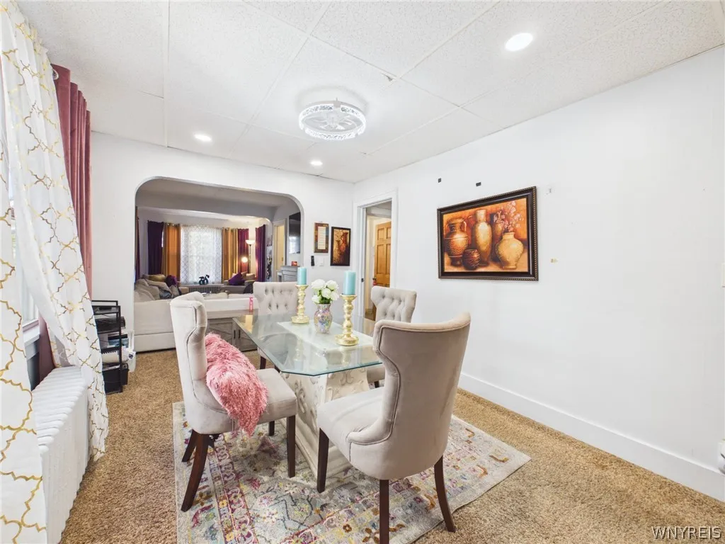 Dining room: A formal dining room with recessed lighting, a modern ceiling light, large side windows and an arched opening into the living room.