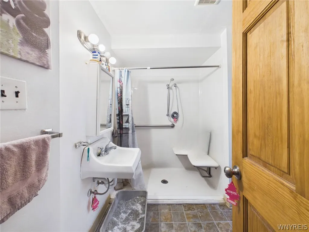 Bathroom: A walk-in shower with a low threshold, a handheld showerhead, a grab bar and a fold-down seat.