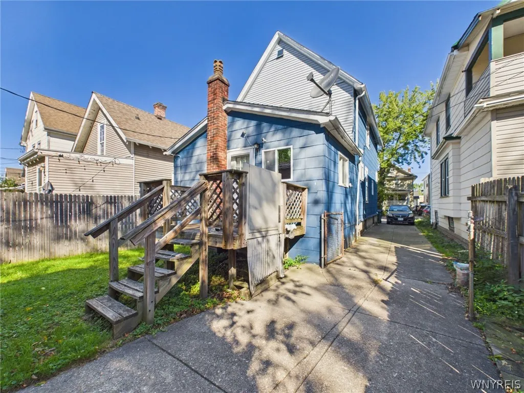 Rear drive view: The driveway runs from the back of the house to the street, with a chain link gate into the yard.