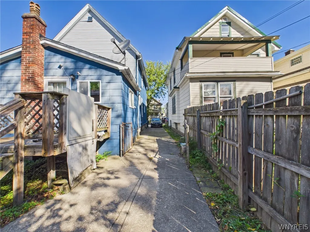 The back of the house, with a raised wood deck, stairs down to the yard and the driveway.