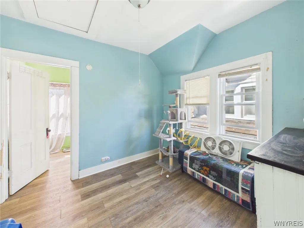 2nd Bedroom or A large bedroom with sloped ceilings, a painted accent wall, abundant natural light, wood-look flooring, a closet and a glass-paned exterior door.