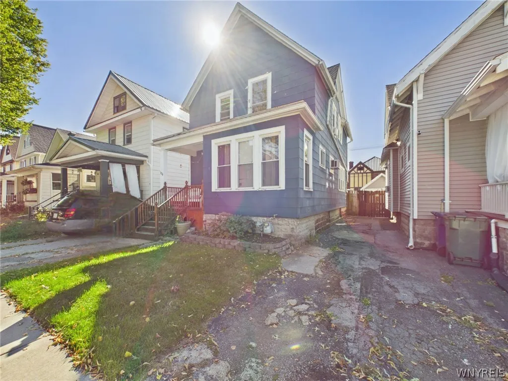 The front from the side, showing the three-window front bay and the side driveway leading to a fenced backyard.