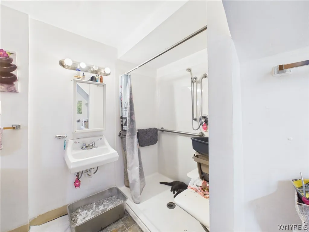 Bathroom, third angle: A view of the wall-mounted sink with the walk-in shower beside it.
