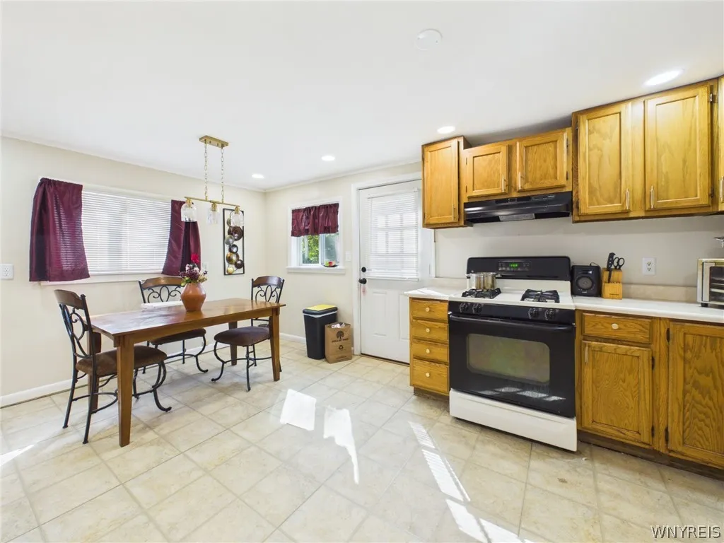 Kitchen: An eat-in kitchen with oak cabinets, a gas range, a range hood, recessed lighting and a side entry door.
