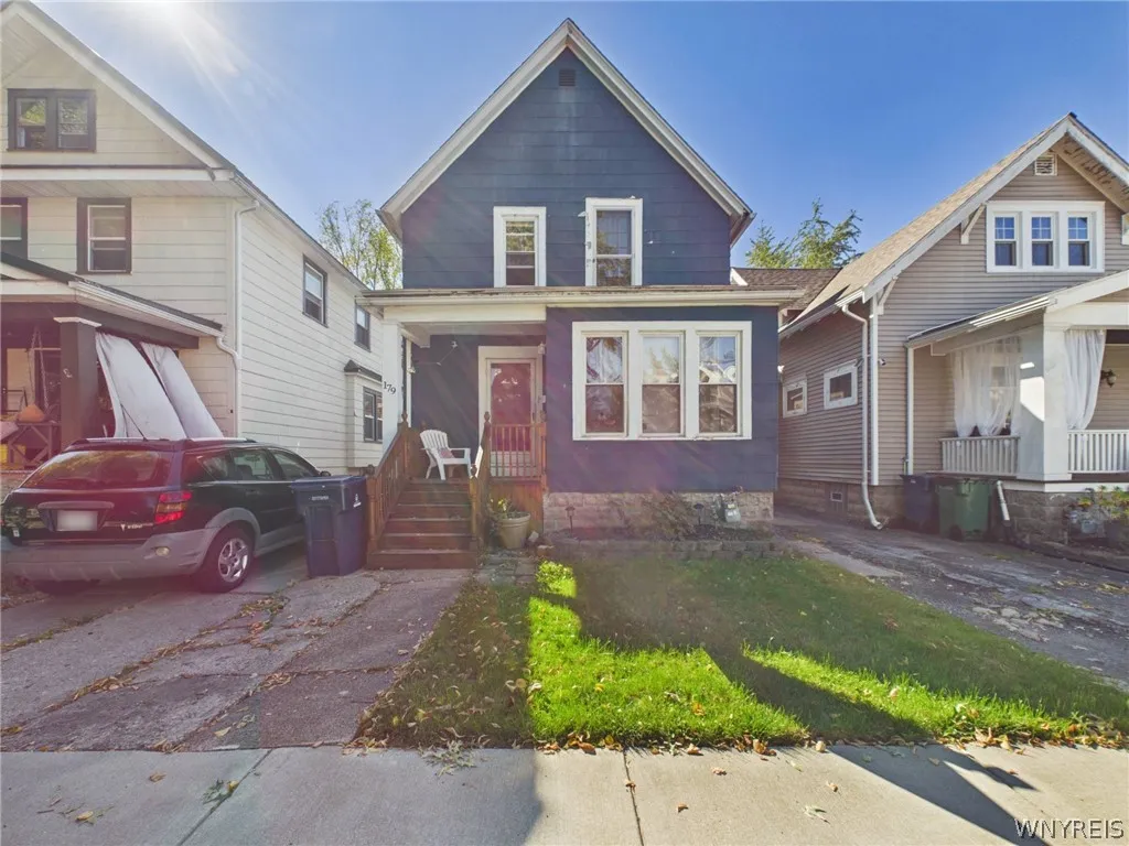 A classic two-story home with blue siding and white trim, a covered front porch with wood steps, and a front lawn.